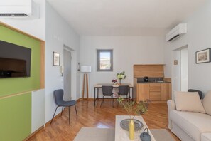 A compact living space with a dining area, kitchenette, and a sofa.