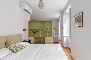 A modern bedroom with a bed, a green shelving unit, a desk, and a chair.