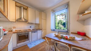 A modern kitchen with white cabinets, stainless steel appliances, a large window, and a dining area with wicker chairs. - 🏠 PROPERTY DESCRIPTIONCasa Valentina is located in a typical Ligurian building, in a central area near the charming harbor of Camogli.It is the perfect starting point for a seaside holiday without the need to use a car or public transport.In just 5 mi (Camogli)