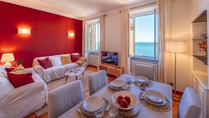 A modern living room with a dining area, red walls, and a view of the sea. - 🏠 PROPERTY DESCRIPTIONCasa Valentina is located in a typical Ligurian building, in a central area near the charming harbor of Camogli.It is the perfect starting point for a seaside holiday without the need to use a car or public transport.In just 5 mi (Camogli)