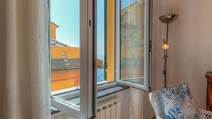 Ein Zimmer mit Fenster, Heizkörper, Stuhl und Stehlampe.