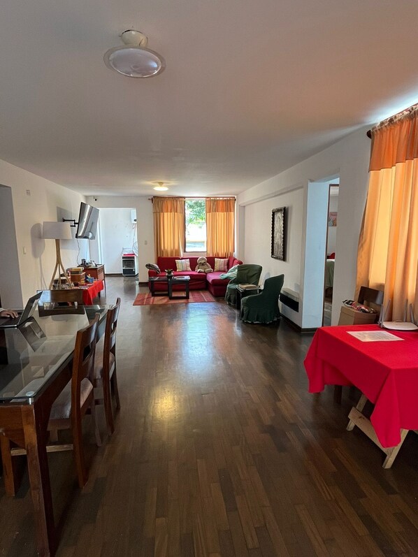 Un amplio espacio de estar con una mesa de comedor, sillas, un sofá y un mantel rojo.