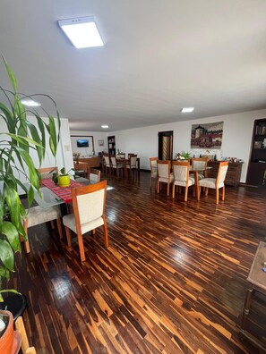 Un comedor amplio con piso de madera, varias mesas y sillas.