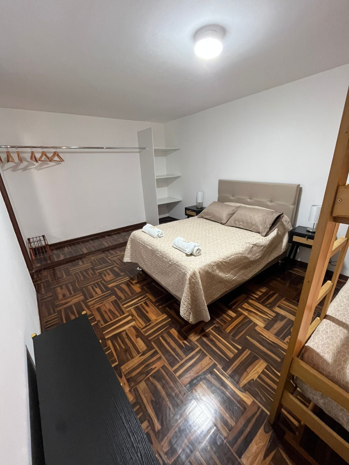 A bedroom with a bed, a bedside table, a hanging light fixture, and a wardrobe.