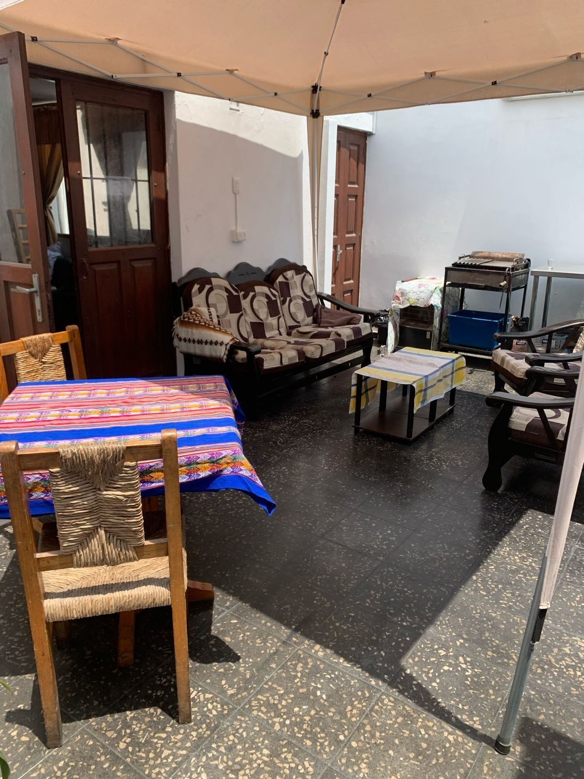 Un patio al aire libre con una mesa y sillas, un sofá y una pequeña mesa con mantel.