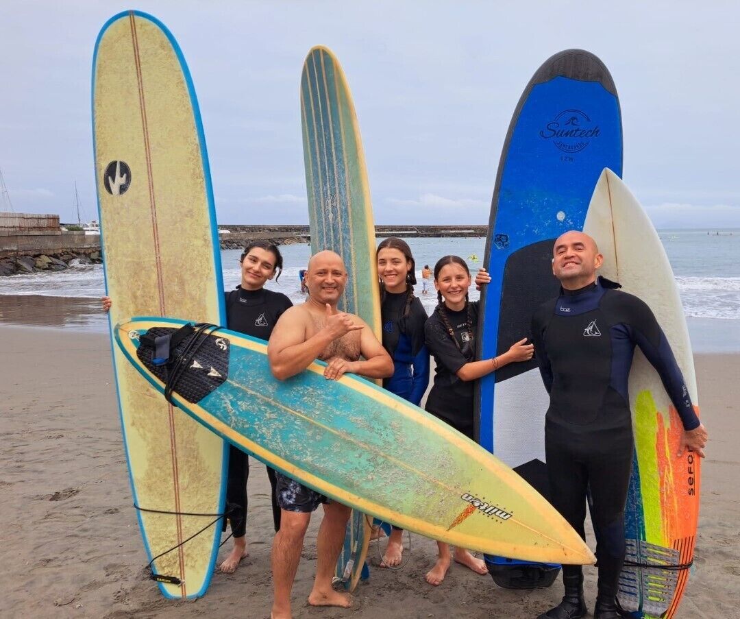 A group of people holding surfboards on a beach.