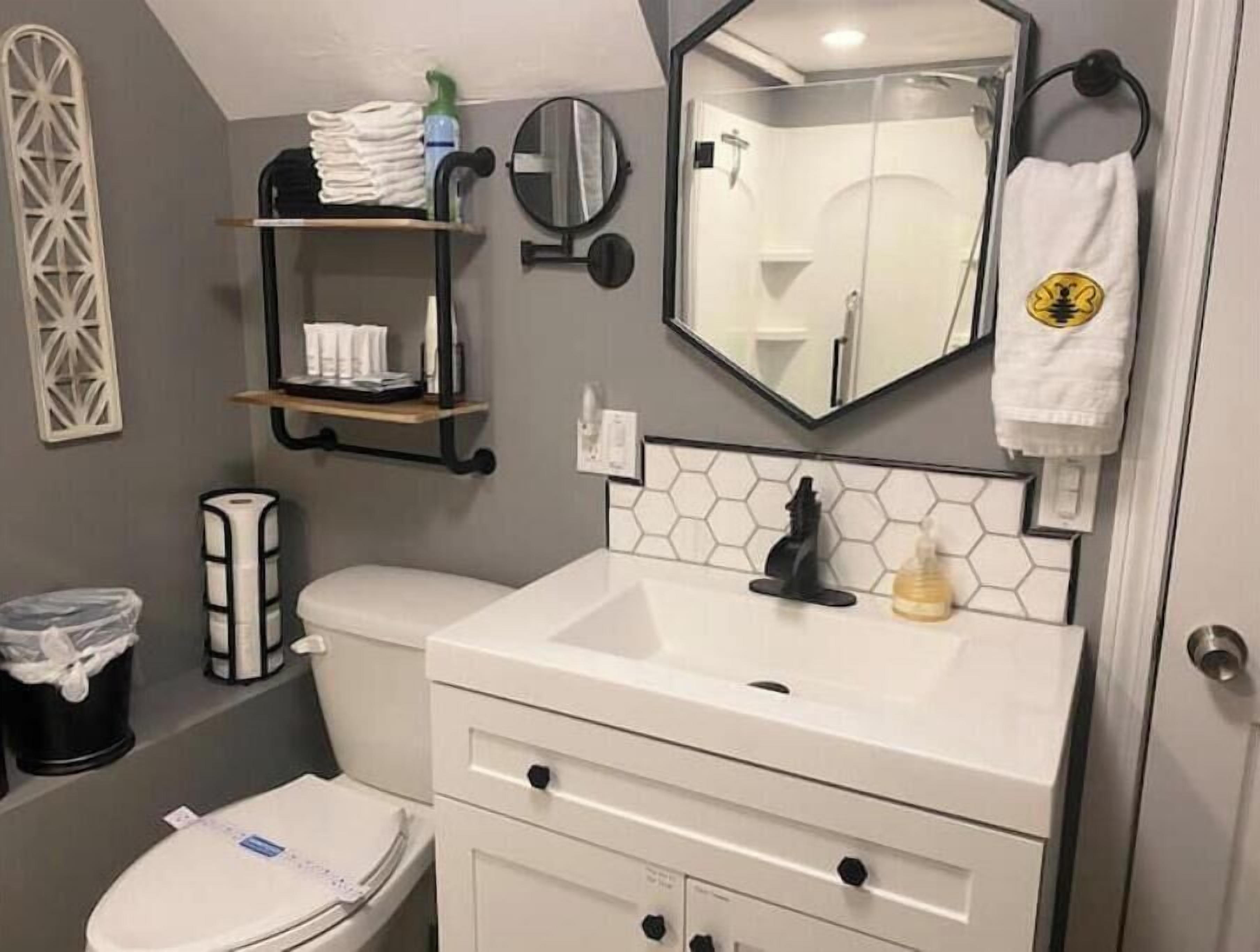 Un baño con inodoro, lavamanos, espejo y toallero.