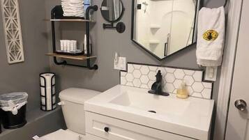Un baño con inodoro, lavamanos, espejo y toallero.