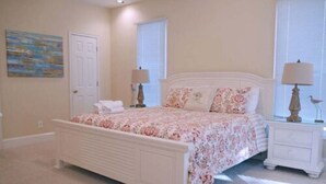 A bedroom with a bed, nightstands, a door, and a window. - 4C & Sand • Private Pool • Steps to Beach (St. George Island)
