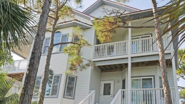 A multi-story building with a balcony on the second floor, surrounded by trees. - 4C & Sand • Private Pool • Steps to Beach (St. George Island)