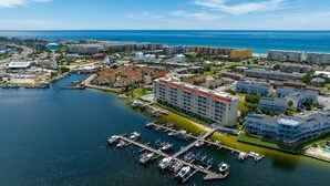 Vista aérea de un pueblo costero con un puerto deportivo, edificios y una torre distintiva.