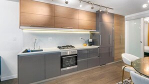 Una cocina moderna con armarios grises, horno integrado y campana extractora de acero inoxidable.