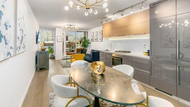 Una cocina moderna con una mesa de vidrio, sillas blancas y una lámpara de techo original.