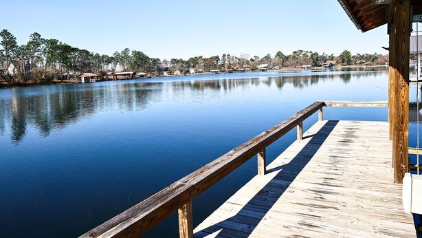 Un muelle de madera que se extiende sobre aguas tranquilas, con un edificio a la derecha.