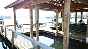 Un muelle de madera con un área de descanso cubierta que da a una masa de agua tranquila.