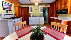Une cuisine de taille réduite avec des meubles blancs, une cuisinière et une table à manger agrémentée d’un set de table rouge.