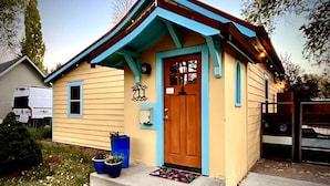 Une petite maison de plain-pied avec une porte bleue et un petit porche.