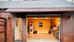 A garage with a metal roof, a washing machine, and a broom. - Joe's Bike Shop w/ Garage and EV Charging (Flagstaff)