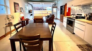 A modern kitchen with white cabinets, a stainless steel oven, and a dining area with a wooden table and chairs. - Joe's Bike Shop w/ Garage and EV Charging (Flagstaff)