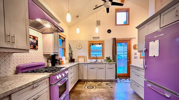 Una cucina con un piano cottura viola, pensili e una ventola a soffitto.