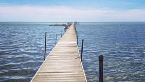 Un muelle de madera que se adentra en aguas tranquilas, bajo un cielo despejado.