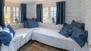 Una habitación acogedora con dos camas, cortinas azul oscuro y un pequeño ventanal con una planta.