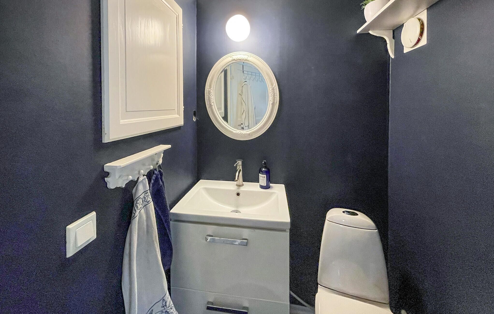 Une salle de bain avec un lavabo blanc, un miroir, un porte-serviettes et des toilettes.