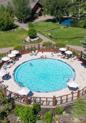 A circular pool with a wooden deck, lounge chairs, and umbrellas. - Luxurious Remodel- Walking Distance & Resort Pool Access (Sun Valley)