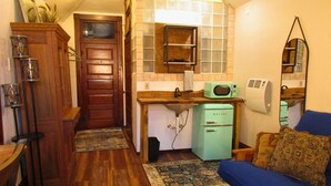 Un espacio habitable compacto con kitchenette, un sofá azul y una alfombra estampada.