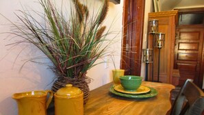 Una mesa de comedor de madera con un florero tejido, una jarra amarilla y un tazón verde sobre un plato a juego.