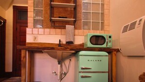 Cocina compacta con un refrigerador Galanz, un microondas y un lavamanos debajo de una encimera de madera.