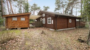 Eine Holzhütte mit Veranda und einem kleinen Nebengebäude.