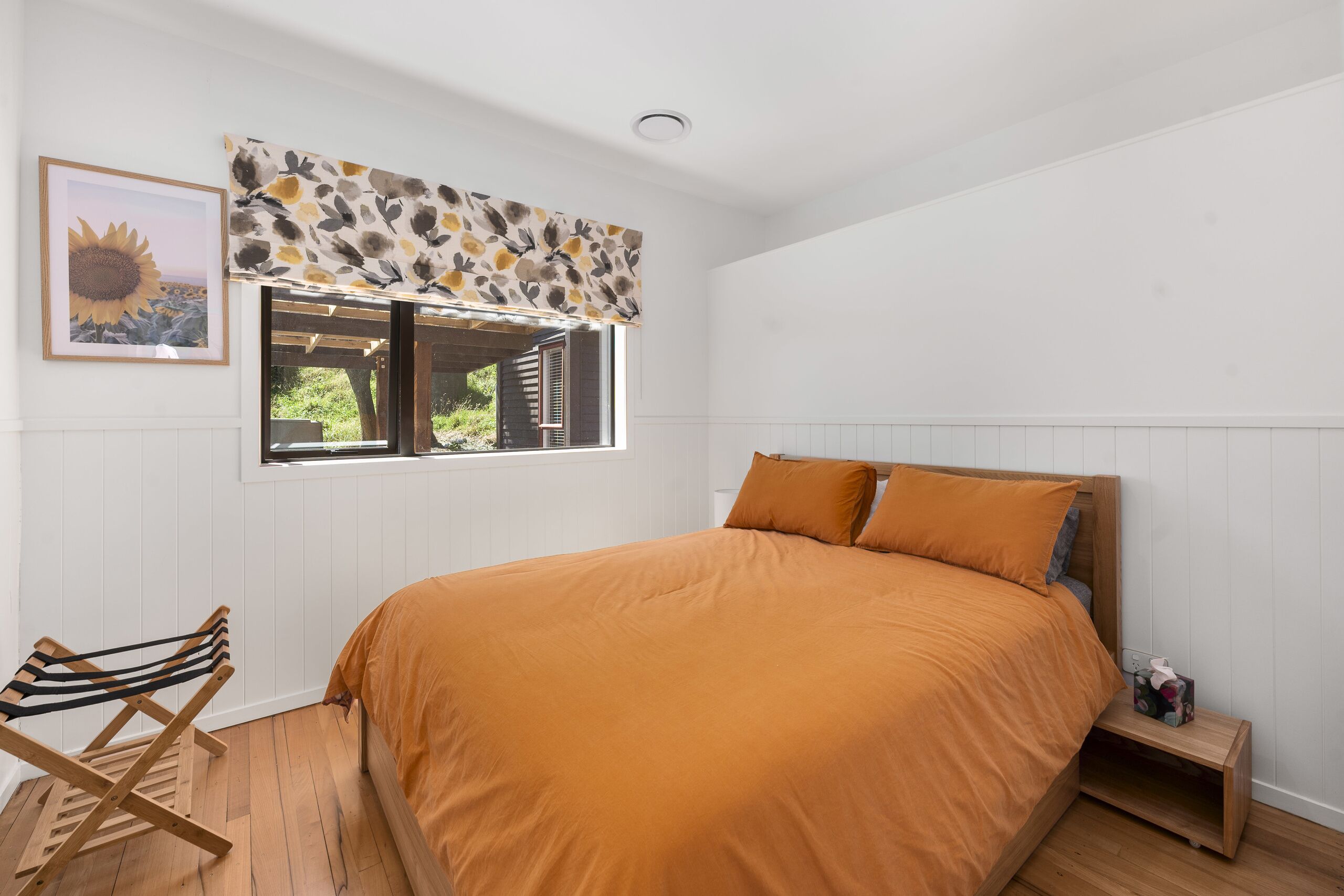 Une chambre avec un lit, une fenêtre donnant sur un beau paysage, une chaise et une petite table.
