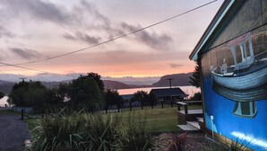 Una casa con vistas a un lago y montañas durante el atardecer.