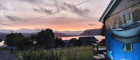 Una casa con vistas a un lago y montañas durante el atardecer.