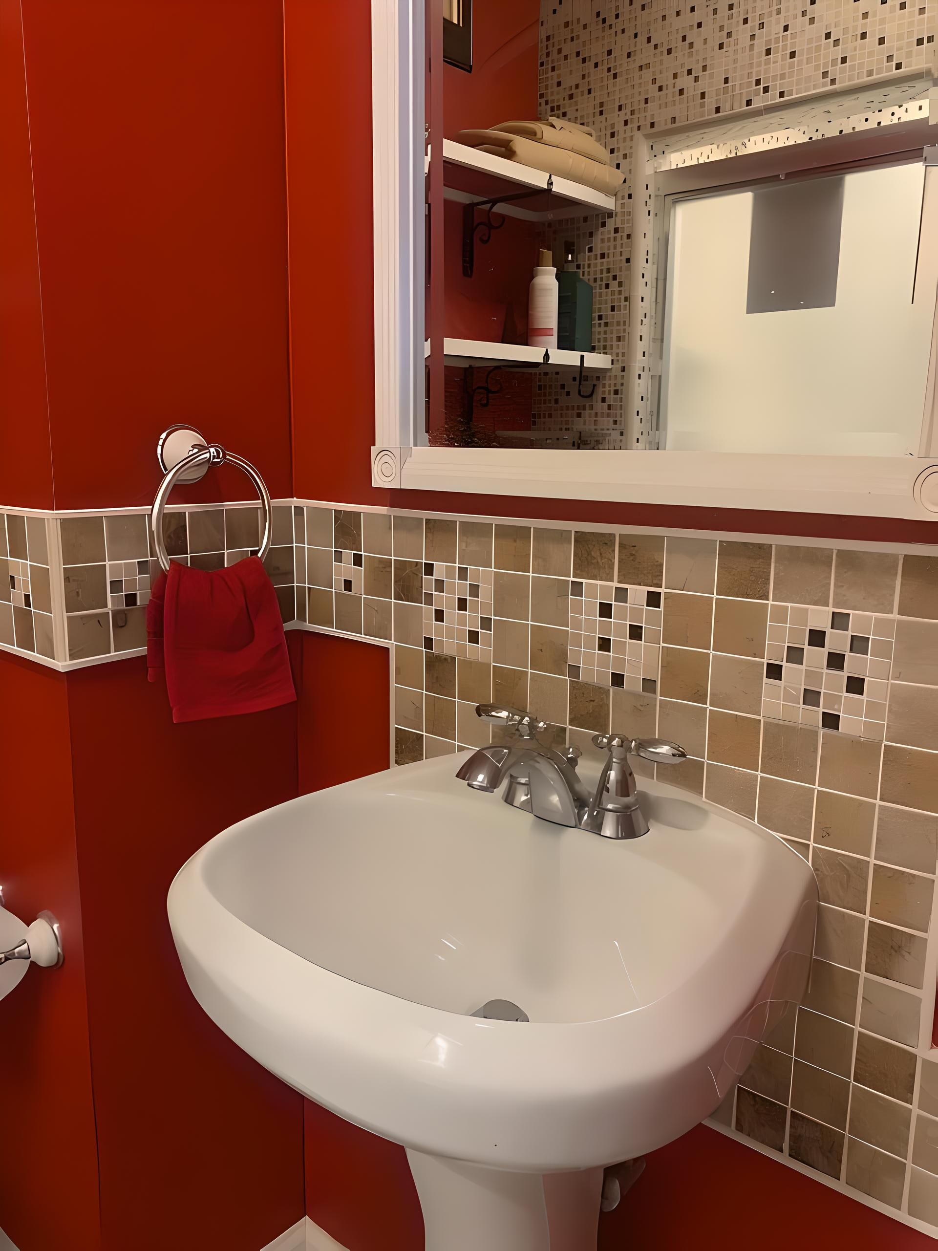 Une salle de bain avec un lavabo blanc, des murs rouges et un pare-feu en carreaux.