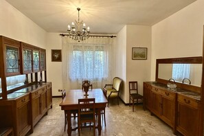 A dining area with a chandelier, wooden cabinets, a table, and chairs. - S325 - Sirolo, four-room apartment in the center with garden and parking space (SIROLO)