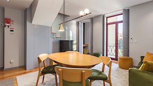 Ein moderner Essbereich mit einem Holztisch und Stühlen, einer Pendelleuchte und Blick ins Freie durch eine Glastür.