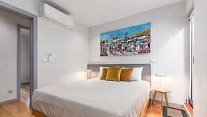 Ein modernes Schlafzimmer mit einem großen Bett, einem Bild an der Wand und einem kleinen Nachttisch.