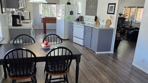 Une cuisine moderne avec un coin repas, comprenant une table et des chaises en bois, un réfrigérateur et une cuisinière.