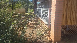 Une cour arrière clôturée, avec un mur en briques, une clôture en bois et un portail en métal.