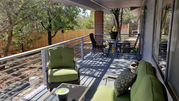 Un espace extérieur aménagé avec un salon de jardin, comprenant un canapé vert, deux fauteuils, une table et une plante en pot.