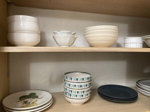 A shelf with various white and patterned bowls and plates.