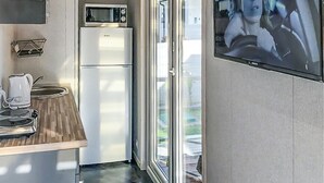 Cocina pequeña con microondas, refrigerador y hervidor sobre la encimera.
