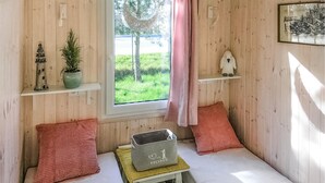 Una habitación acogedora con una cama, una mesita con una cesta y una ventana con vistas al verdor.