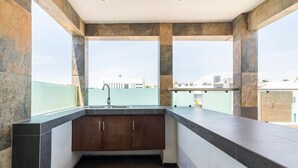 Una cocina moderna con armarios oscuros y un ventanal con vistas a una zona residencial.