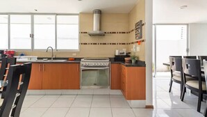 Una cocina moderna con gabinetes de madera, estufa a gas, horno empotrado y un ventanal amplio.