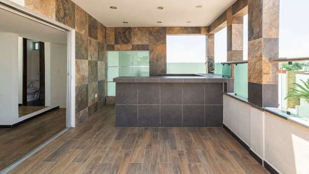 Un baño moderno con un lavamanos grande, paredes con azulejos y suelo de madera.
