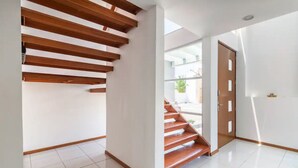 Un interior moderno con una escalera, paredes blancas y suelo de baldosas.
