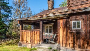 Eine rustikale Holzhütte mit Veranda, Stein Fundament und Schornstein.